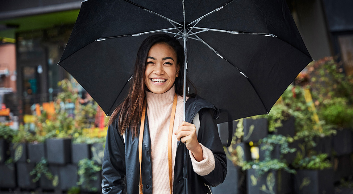 Covered California member smiles outside in the rain.