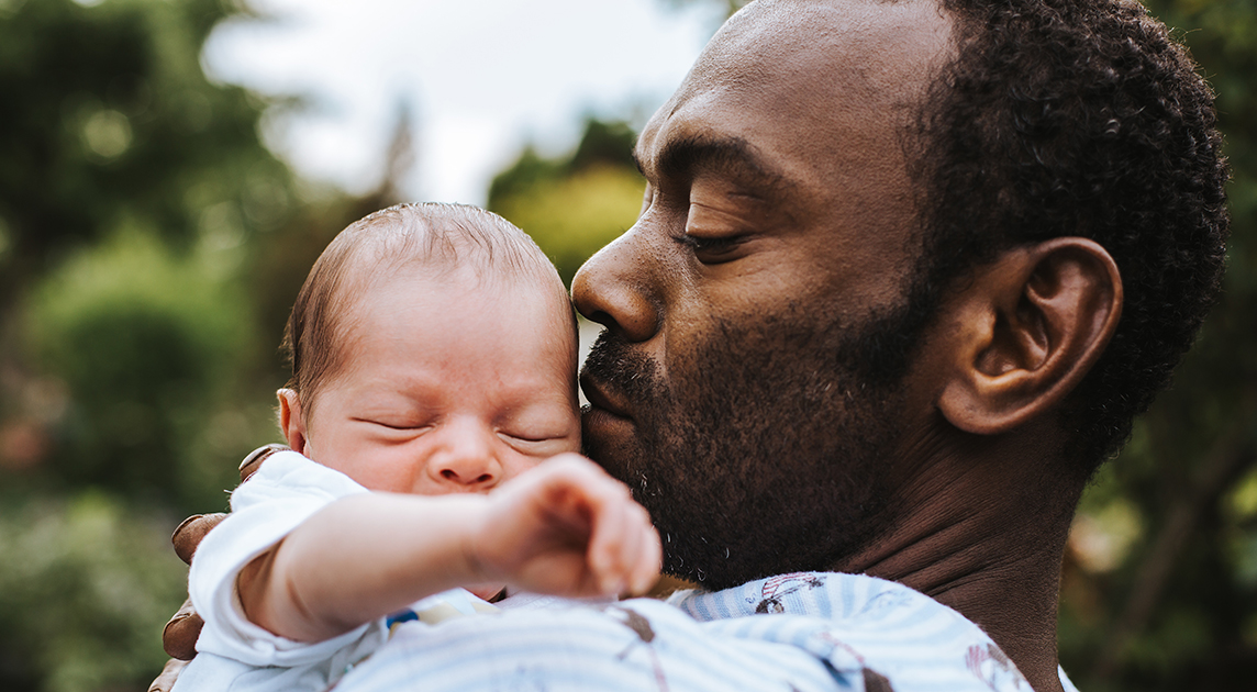 Covered California member and new dad holds his baby.