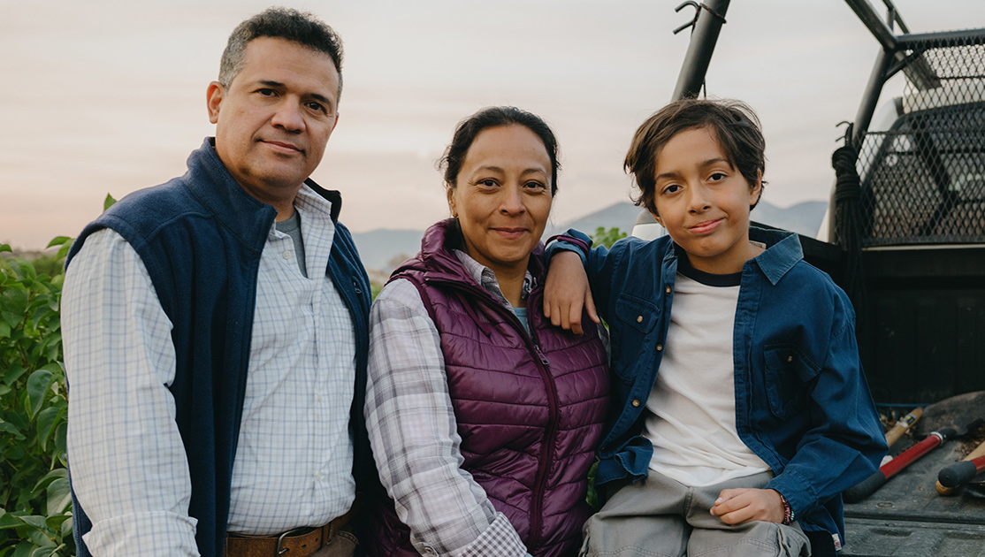 Family of three by a pickup truck in a field